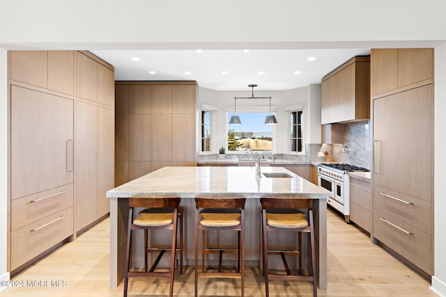 kitchen with modern cabinets, a sink, light stone countertops, and double oven range