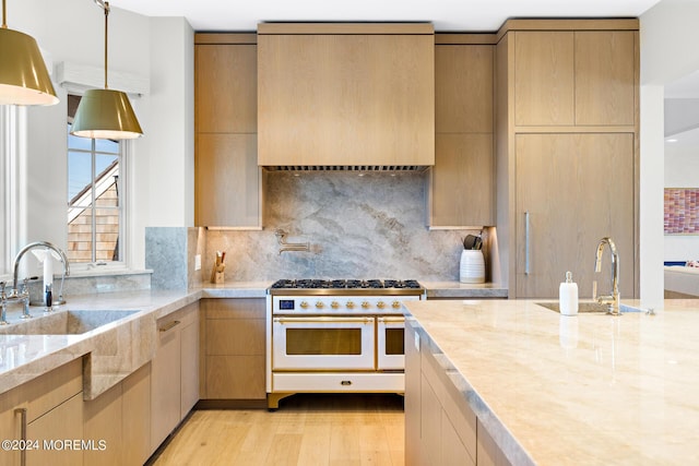 kitchen featuring modern cabinets, a sink, light wood-style flooring, and double oven range