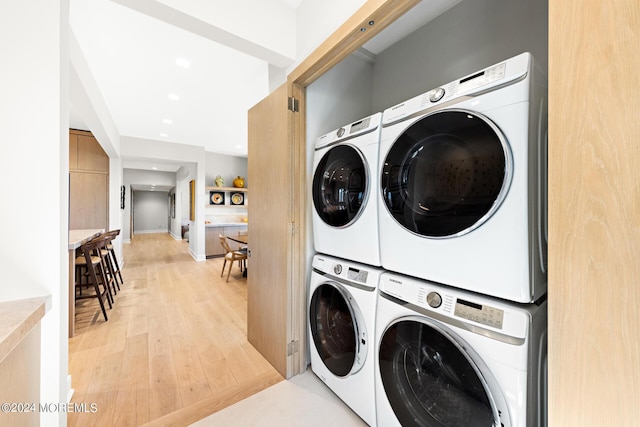 laundry area with laundry area, light wood finished floors, stacked washer / dryer, and recessed lighting