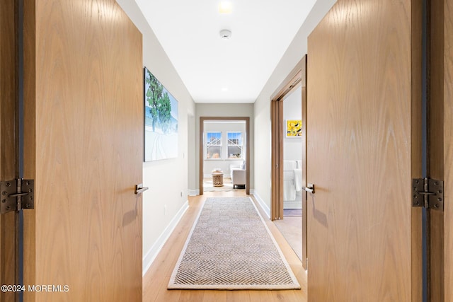 corridor with light wood-style flooring and baseboards