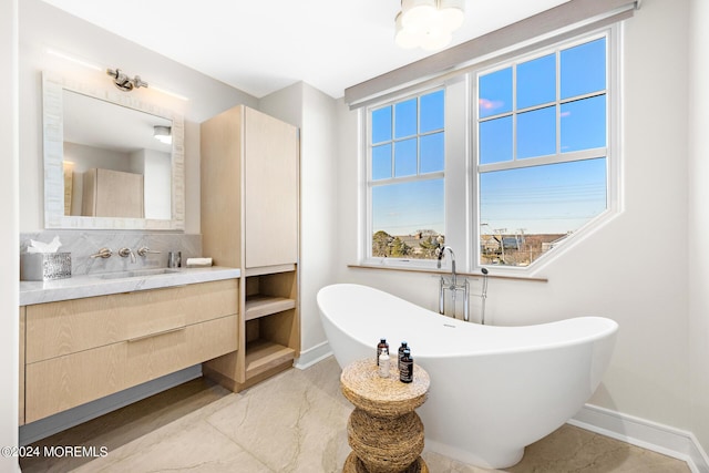 bathroom featuring a freestanding tub, vanity, and baseboards