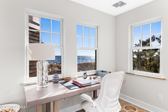 home office with wood finished floors, visible vents, and baseboards