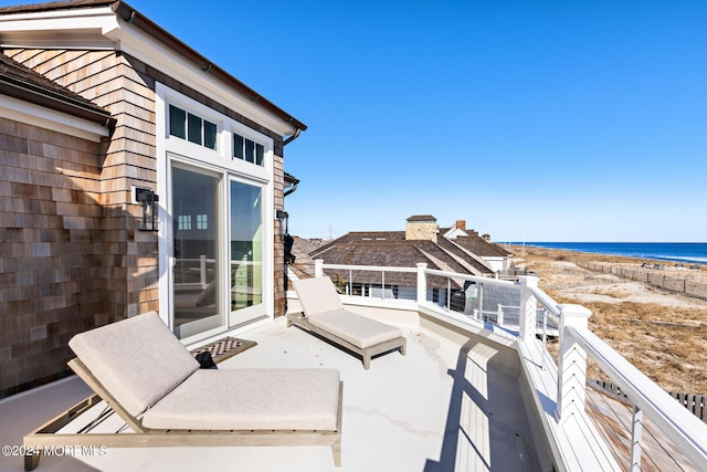 view of patio featuring a beach view, a balcony, and a water view