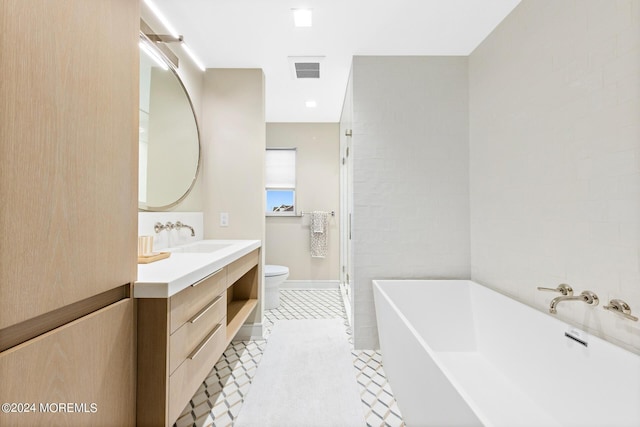 bathroom featuring visible vents, a freestanding bath, toilet, vanity, and tile patterned floors