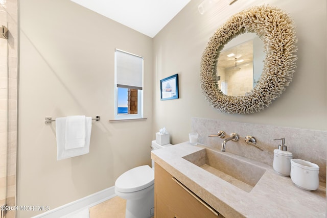 full bath featuring baseboards, a tile shower, vanity, and toilet