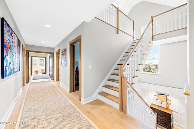 stairs featuring a high ceiling, baseboards, and wood finished floors