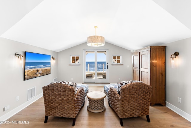 living area with light wood-type flooring, baseboards, visible vents, and vaulted ceiling