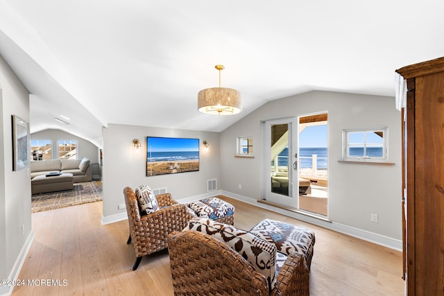 living room with light wood-style flooring, visible vents, vaulted ceiling, and baseboards