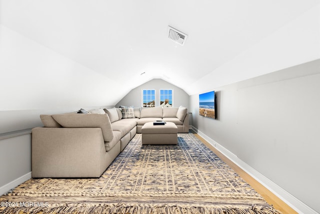 living area with vaulted ceiling, wood finished floors, visible vents, and baseboards