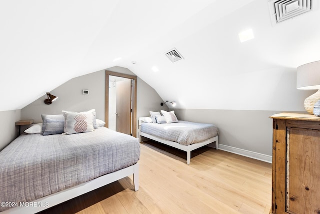 bedroom featuring lofted ceiling, light wood finished floors, baseboards, and visible vents