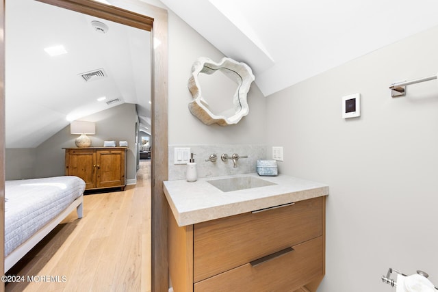 bathroom with visible vents, vaulted ceiling, vanity, and wood finished floors