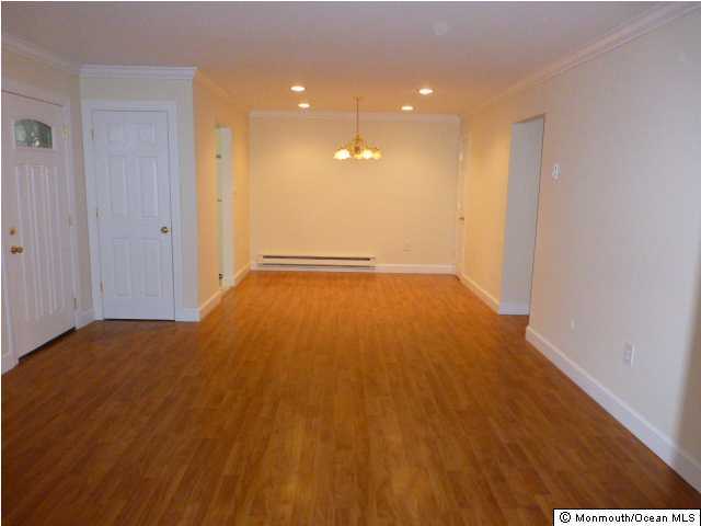 interior space featuring a notable chandelier, a baseboard radiator, ornamental molding, wood finished floors, and baseboards