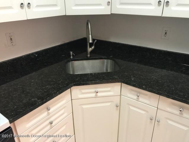 kitchen featuring dark countertops, white cabinets, and a sink