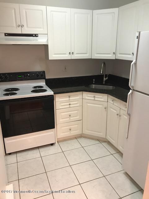 kitchen featuring electric stove, freestanding refrigerator, white cabinetry, a sink, and under cabinet range hood