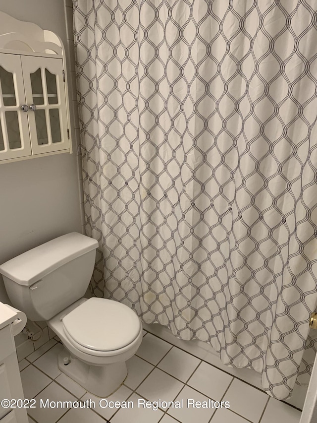 bathroom with vanity, curtained shower, tile patterned flooring, and toilet