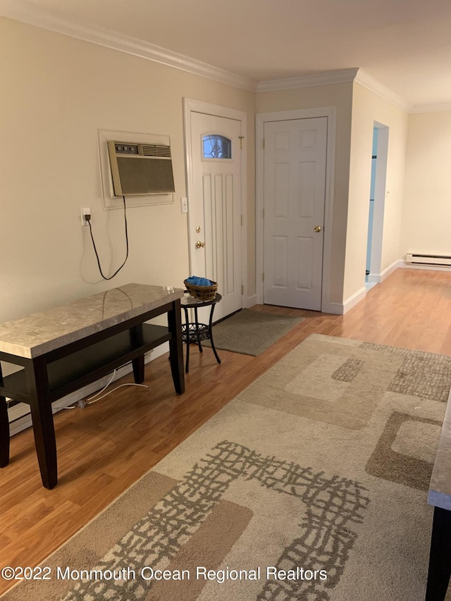 foyer featuring baseboards, wood finished floors, crown molding, and a wall mounted AC