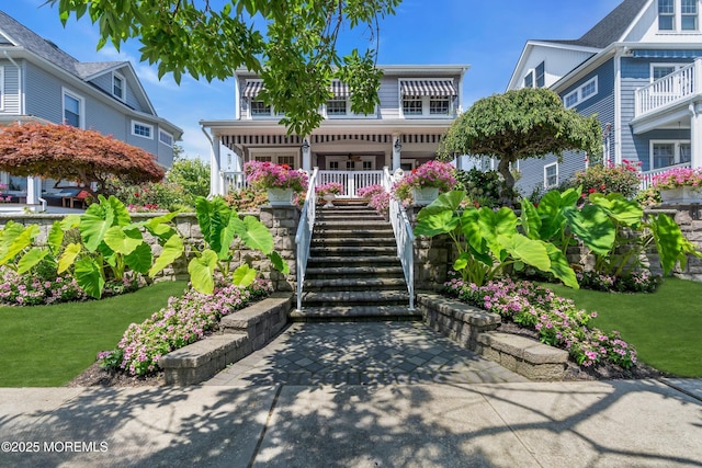 view of front of house with covered porch, stairway, and a front lawn