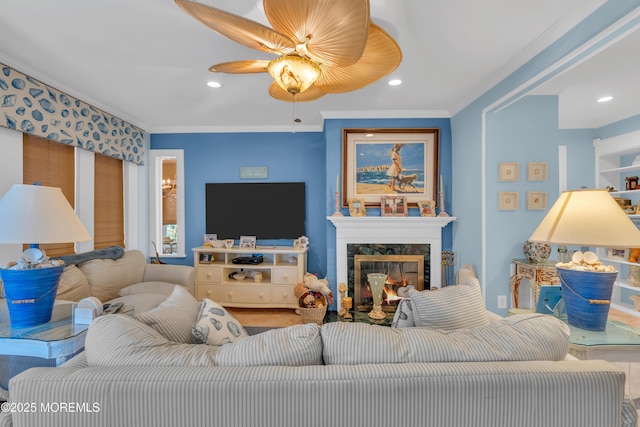 living room featuring ceiling fan, a premium fireplace, crown molding, and recessed lighting