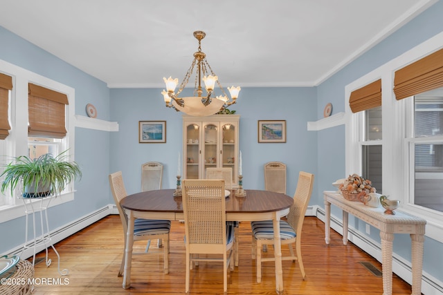 dining space featuring a chandelier, baseboard heating, light wood-type flooring, and visible vents