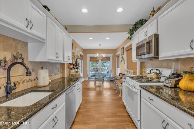 kitchen with a notable chandelier, a sink, white cabinets, appliances with stainless steel finishes, and light wood-type flooring