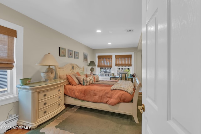 bedroom with a baseboard radiator, multiple windows, visible vents, and recessed lighting