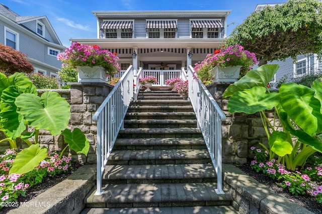 back of house with covered porch, stairway, and a ceiling fan