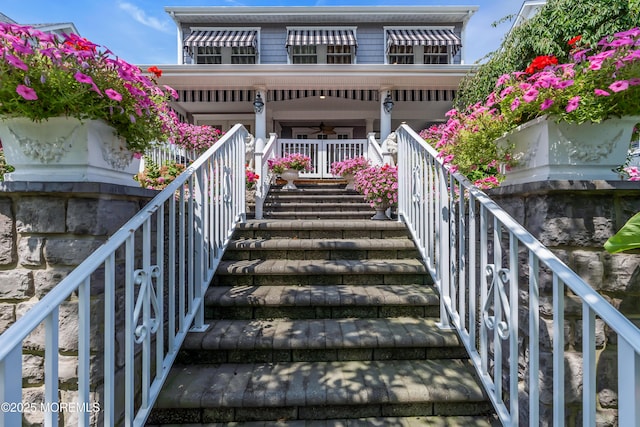 rear view of house featuring a ceiling fan, covered porch, and stairway