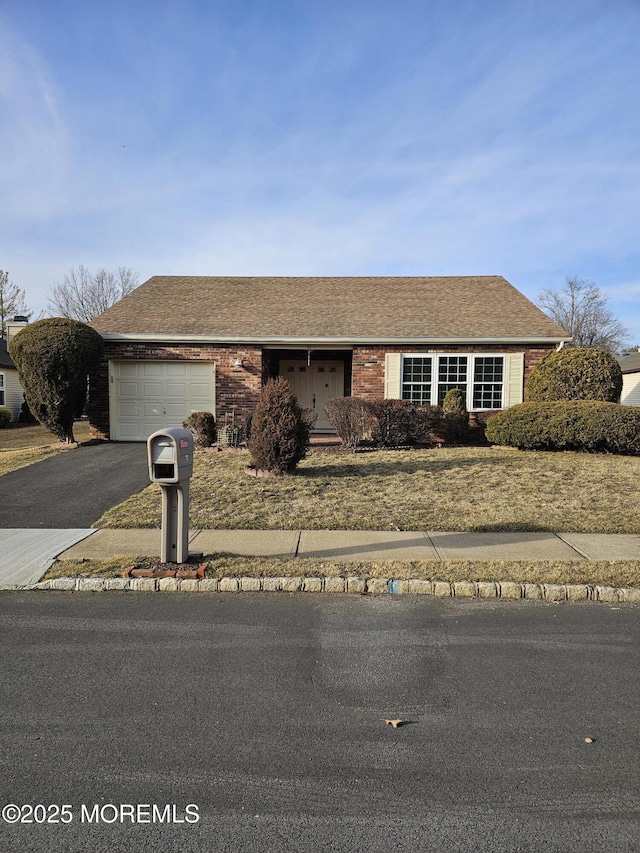 single story home featuring aphalt driveway, roof with shingles, an attached garage, and brick siding