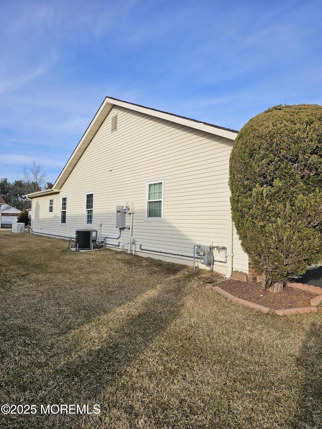 view of property exterior featuring central AC unit and a lawn