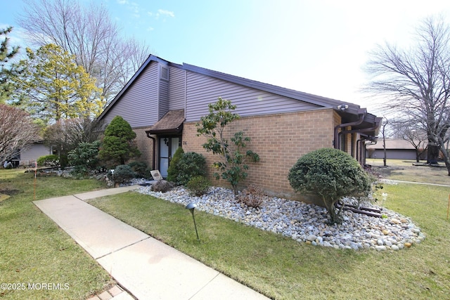 view of property exterior with brick siding and a lawn