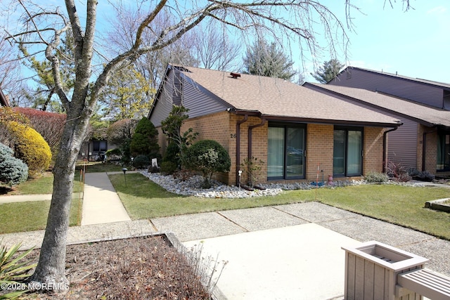 view of property exterior with a yard, brick siding, and roof with shingles