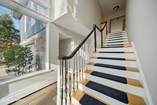 stairs with a high ceiling and wood finished floors