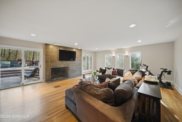 living room featuring recessed lighting, baseboards, a tiled fireplace, and wood finished floors