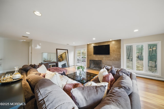 living room featuring a fireplace, recessed lighting, visible vents, baseboard heating, and wood finished floors