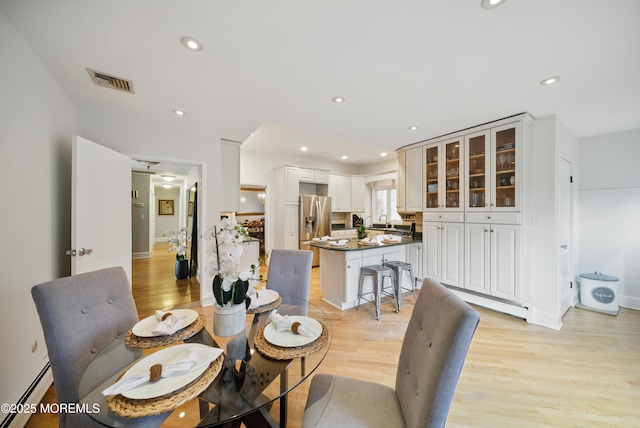 dining area with light wood-style floors, a baseboard radiator, visible vents, and recessed lighting