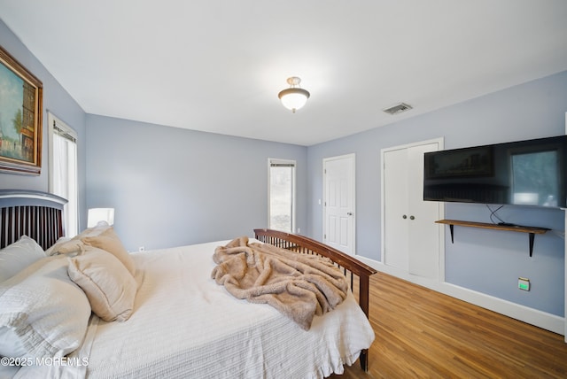 bedroom featuring baseboards, visible vents, and wood finished floors