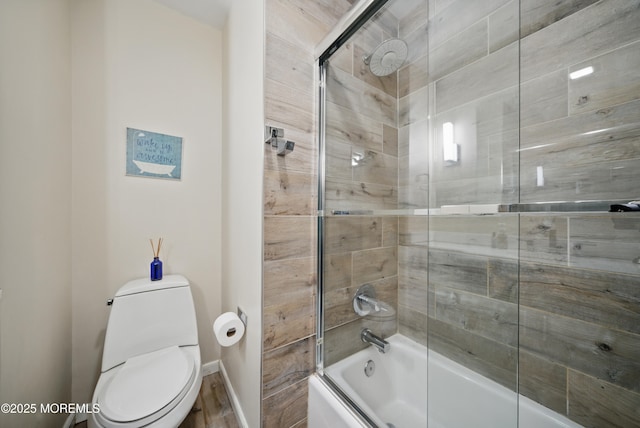 bathroom with toilet and bath / shower combo with glass door