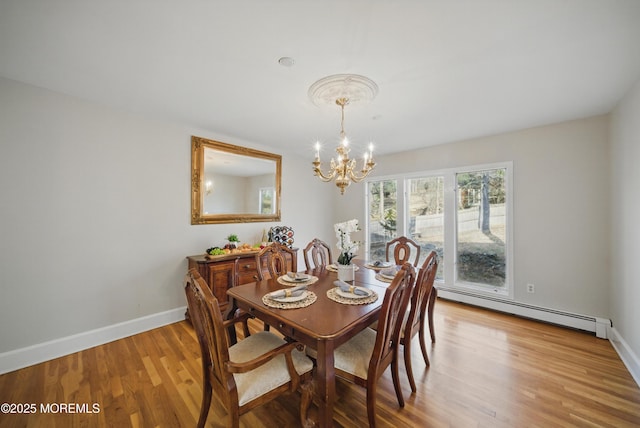 dining room with baseboards, a chandelier, baseboard heating, and wood finished floors