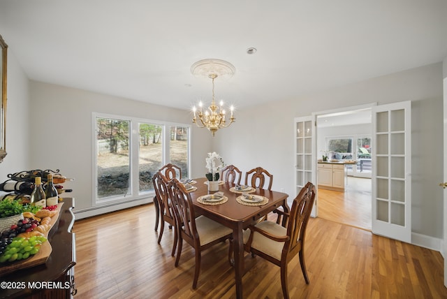 dining area with a baseboard heating unit, a chandelier, and light wood-style floors