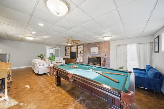 recreation room with pool table, a fireplace, a drop ceiling, and baseboards