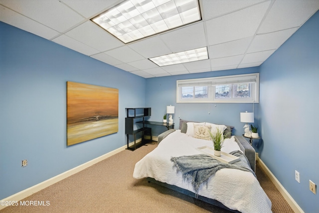 carpeted bedroom with a paneled ceiling and baseboards