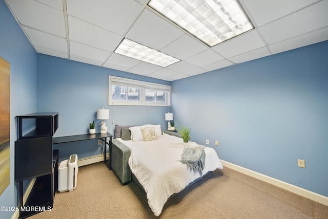 bedroom with baseboards, a baseboard heating unit, a drop ceiling, and carpet flooring