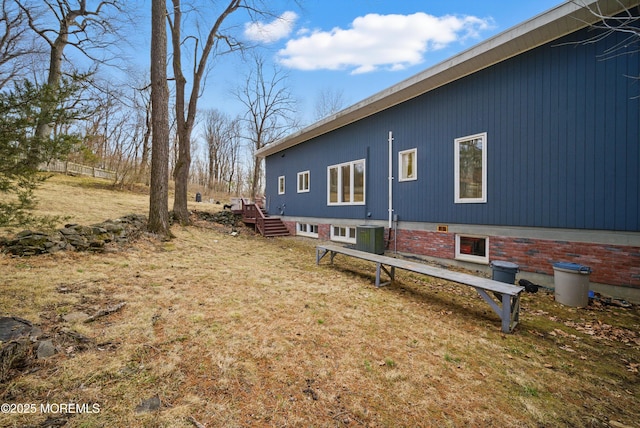 view of home's exterior with a yard, central AC, and brick siding