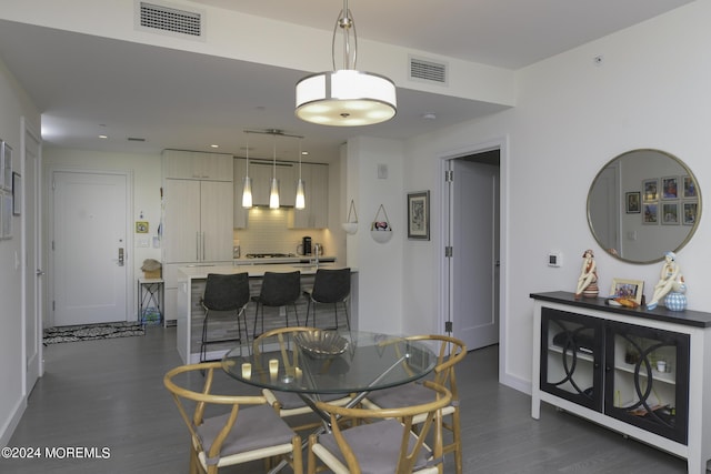 dining space featuring dark wood-style floors, visible vents, and baseboards