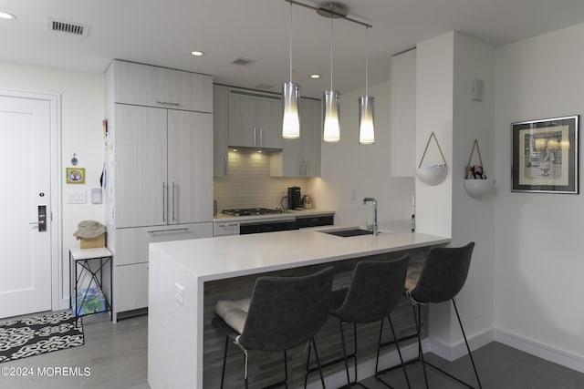 kitchen featuring tasteful backsplash, visible vents, a breakfast bar, stainless steel gas stovetop, and a sink