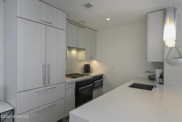 kitchen featuring wall oven, stainless steel gas cooktop, a sink, visible vents, and black oven