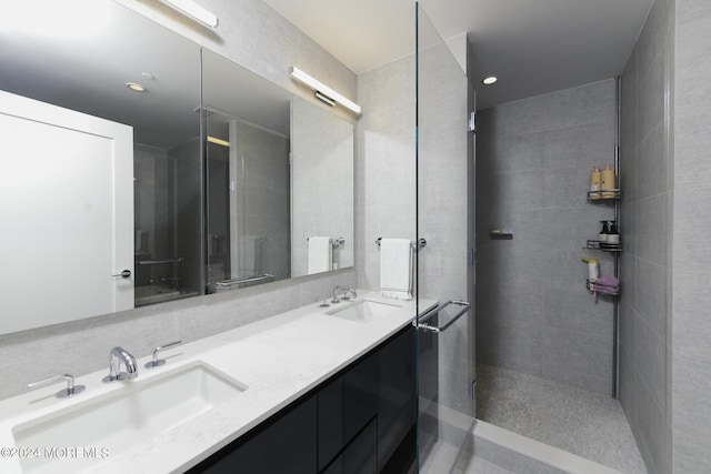 bathroom with a tile shower, double vanity, a sink, and recessed lighting