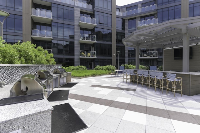 view of patio featuring a grill, outdoor dry bar, area for grilling, and a pergola