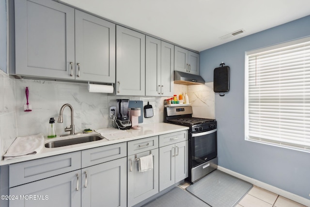 kitchen with visible vents, gray cabinetry, stainless steel range with gas stovetop, a sink, and under cabinet range hood