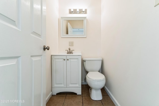 half bathroom featuring toilet, tile patterned flooring, baseboards, and vanity